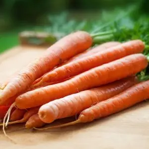 Frische Karotten auf einem Holztisch als Symbol für Vitamin-A-reiche Ernährung.